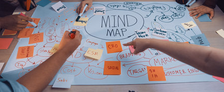A dynamic brainstorming session captures multiple hands working together on a vibrant mind map detailing diverse marketing strategies and innovative concepts.の写真素材