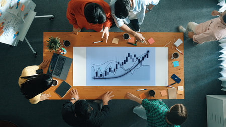 A diverse team engages in a collaborative business meeting, analyzing charts and data on a modern...