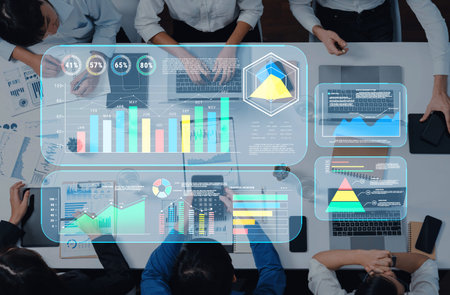 A group of professionals collaborates over a table filled with digital devices, focusing on data...