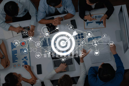 A dynamic business meeting showcases a team focused on strategy development using charts and interactive digital tools to drive marketing targets and collaboration.の写真素材