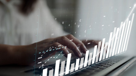 A professional individual is using a laptop, engaging in data analysis. Graphs and financial metrics...