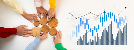 Hands gather around wooden gears and financial charts, symbolizing collaboration in business...