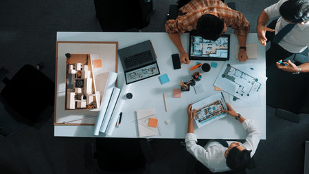 Architect team discussing and pointing and presenting blueprint to interior designer. Aerial view professional business people brainstorming building interior at table with house model.の写真素材