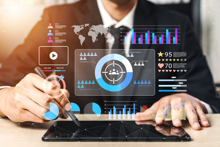 A business professional uses a tablet to analyze data, with digital graphs and charts illustrating...