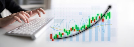 A focused scene showing hands typing on a keyboard next to a financial chart that illustrates an...
