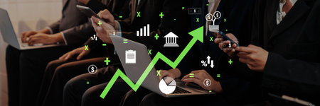 A group of business professionals in a modern office collaboration, using digital devices to analyze data trends and develop financial strategies for future growth.の写真素材