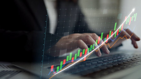 A business professional engages with stock market data on a laptop, showcasing growth trends through...