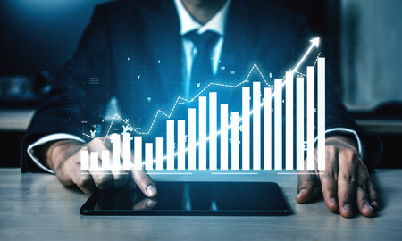 A businessman is analyzing data on a tablet, showcasing a growing bar chart in a modern office. The...