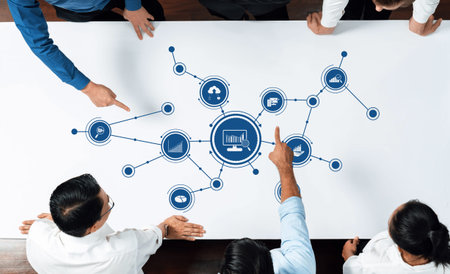 Professionals engage in data analysis, pointing to charts and graphs on the table while utilizing...