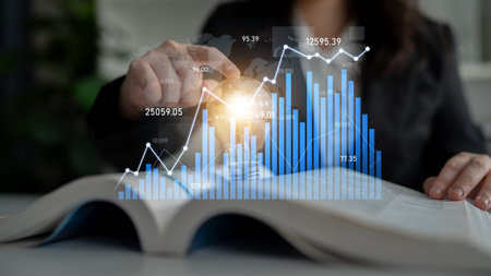 A professional setting features a person analyzing financial charts and graphs over an open book,...