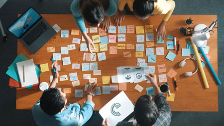 Top view of business team put graphic logo on meeting table with colorful sticky notes and start to...