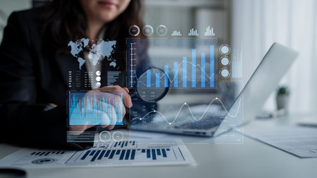 A professional businesswoman focuses on digital data analysis in a modern office, examining statistical growth and insights with advanced charts and graphs.の写真素材