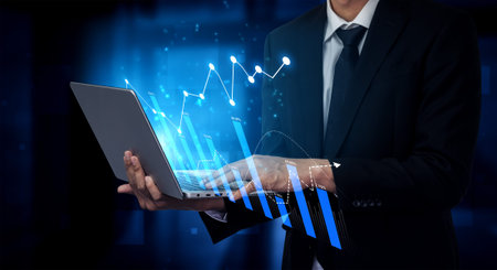 A businessman in a suit interacts with a laptop displaying dynamic data visualizations. The image...