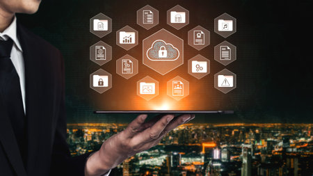 A businessman stands holding a tablet displaying cloud computing security icons against a modern...