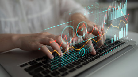 A close-up of hands typing on a laptop keyboard enhanced by digital overlays showing data analytics...
