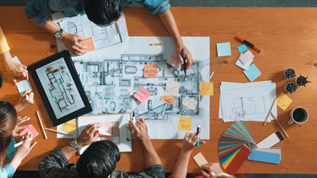Top down aerial view of smart engineer looking at blueprint at meeting room. Skilled architect team...