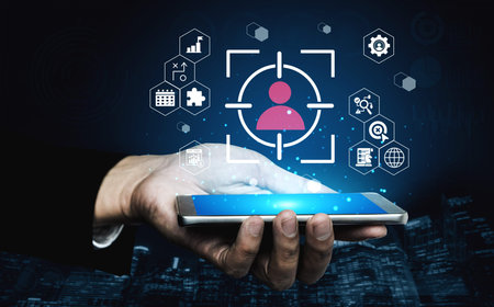 A hand holds a smartphone displaying a person detection interface, surrounded by various icons,...