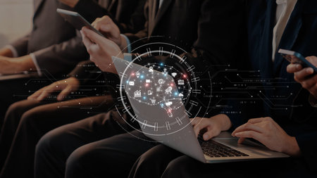 Business professionals engage with various technology devices in a conference setting, showcasing...
