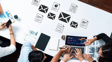 Group Collaboration with Laptops and Documents on Table for Business Strategy and Data Analysis in...