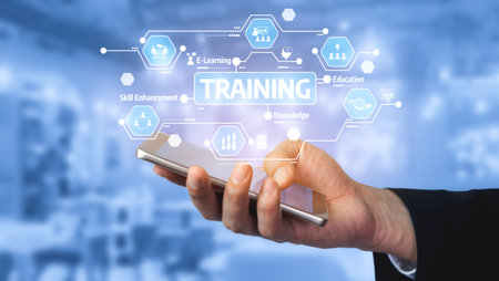 A hand holds a smartphone displaying digital training concepts in a modern workspace, highlighting...