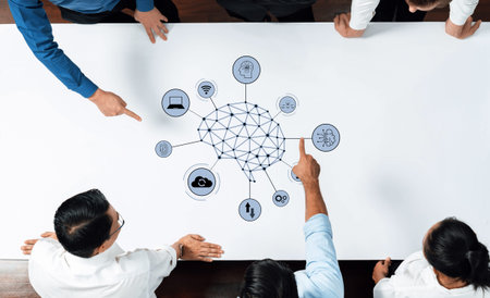 A business team collaboratively analyzes a technology network concept on a table, highlighting...
