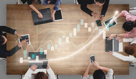 A dynamic business meeting scene featuring participants using laptops and tablets to analyze...