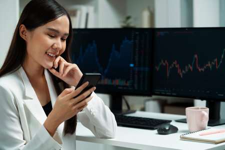 Smiling young Asian businesswoman with happy face looking on smartphone in profitable of exchange...