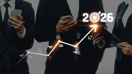 This image features business professionals engaged with smartphones and tablets, showcasing a digital growth chart indicating projections for 2026, symbolizing progress. Rasterの写真素材