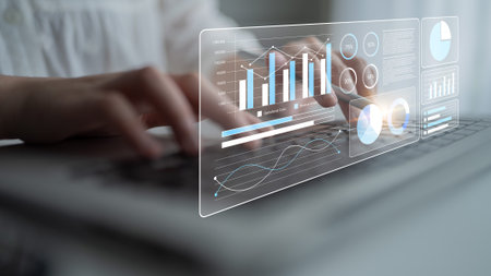 A close-up view showcasing hands typing on a laptop with a dynamic overlay of digital graphs and...