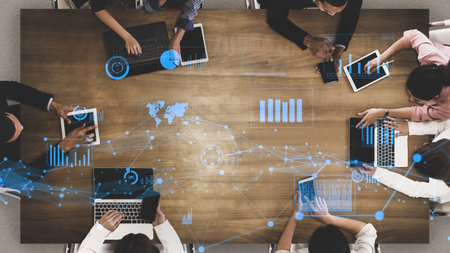 Dynamic overhead view of a diverse business team collaborating with various devices, showcasing data...