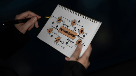 A close-up view of hands holding a notebook featuring a file management diagram, highlighting key...
