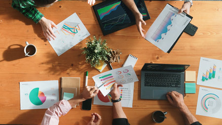Top down view of smart business people hand working together to analyze chart. Skilled marketing team discussing about financial plan at table with stock market exchange report placed. Convocation.の写真素材