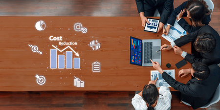 A business team gathers around a wooden table to analyze financial data and graphs, showcasing...