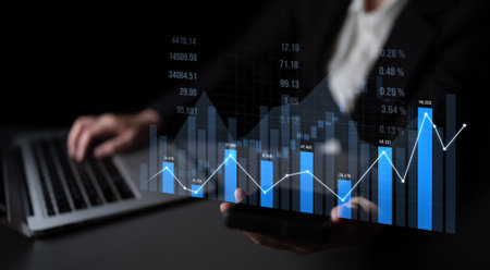 A business professional reviews data trends on a laptop and smartphone, highlighting important...