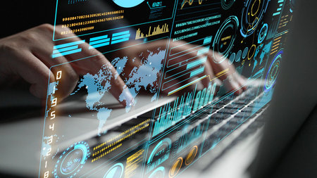 A close-up of hands typing on a laptop, layered with digital interface graphics showcasing data...