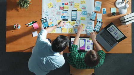 Time lapse of smart manager working together to develop Ux Ui design for mobile interface. Developer partner working together discussing about changing software app while using on laptop. Convocation.