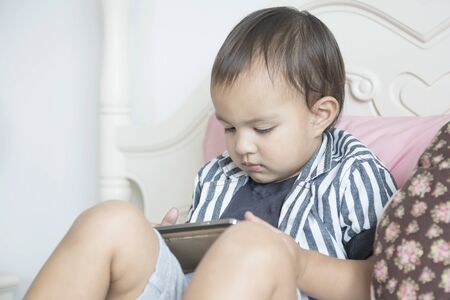 Cute Little boy using mobile phone at homeの写真素材