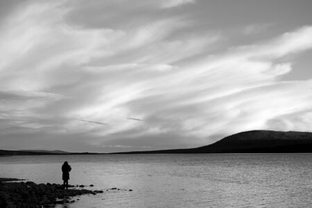 Woman nature silhouettes against the sky and clouds along the coast. The image black and white.の写真素材
