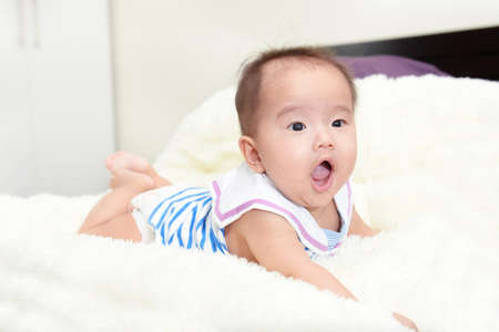 asian cute baby sitting on a soft cloth in the living room.