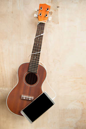 ukulele with phone on wood backgroundの写真素材