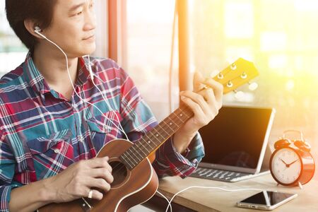 Handsome man are studying to play ukulele.