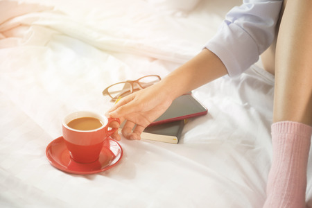 Beautiful woman drinking coffee on bed, in the morning.の写真素材