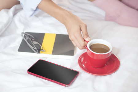 Beautiful woman drinking coffee on bed, in the morning.の写真素材