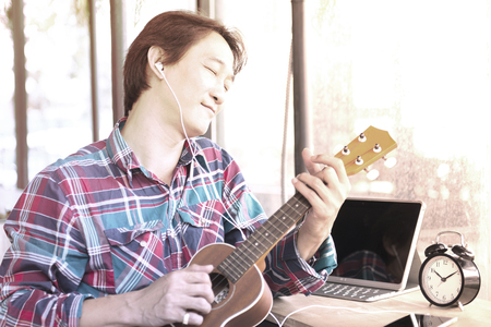 Handsome man are studying to play ukulele.の写真素材