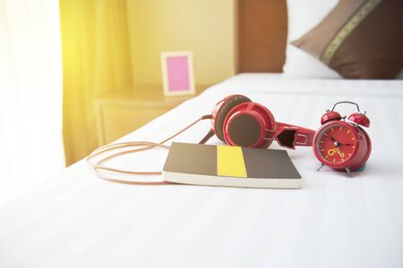 Note and the clock on the bed in the bedroom.の写真素材