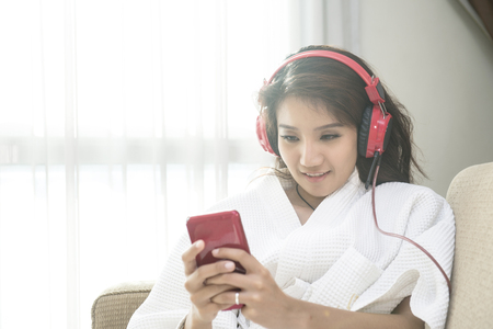 Beautiful woman playing phone in bedroom happily in morning.の写真素材
