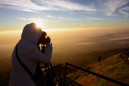 Silhouettes of tourists are photographing the mountain mist and sunrise.の写真素材