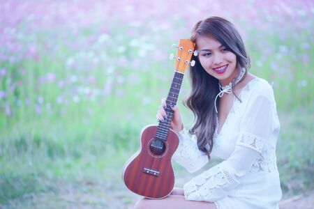 Pretty woman happy in the midst of nature, with a beautiful flower in a sunset.の写真素材
