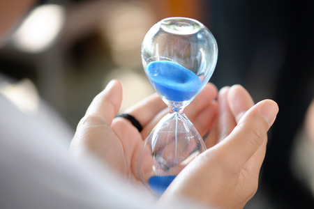 Hourglass that is located on the beautiful hands.の写真素材