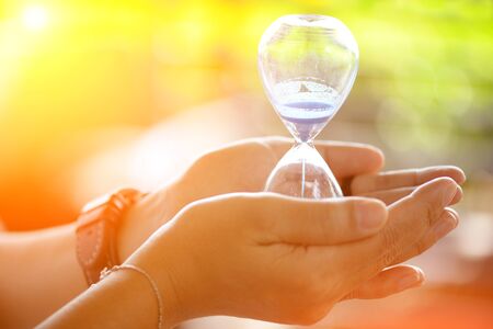 Hourglass that is located on the beautiful hands.